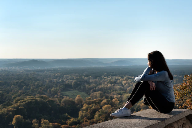 beautiful-girl-sits-hill-looks-into-distance-enjoyment-nature_134398-6462